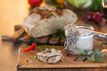 Rustic pâté\pate made from pork liver in a glass jar and a slice of homemade rustic french bread with garlic.