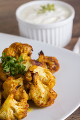 Delicious pork meat and fried cauliflowers as a side dish, served with tartar sauce on a wooden table. Close up.