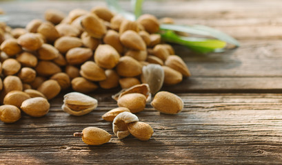 Pile of fresh raw almonds on a rustic wooden table.