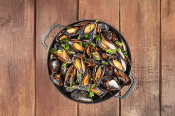 Skillet of marinara mussels on rustic background, overhead shot with copy space