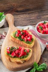 Bruschetta with fresh pesto, basil leaves and tomatoes. Wooden background