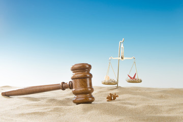 Judge mallet and scales of justice at seaside with copyspace.
