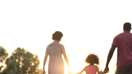 Three person family walking into sunset, happy future together, memories