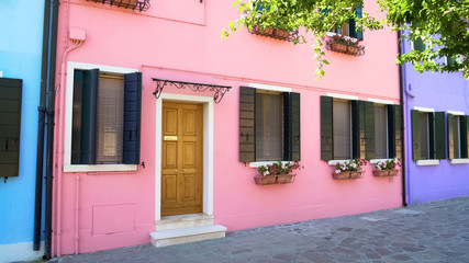 Fototapeta na wymiar Cozy pink house with flowerpots, beautiful colorful building on Burano, Venice