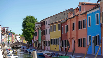 Fototapeta na wymiar Beautiful street with tidy buildings and boats moored along canal, Burano island