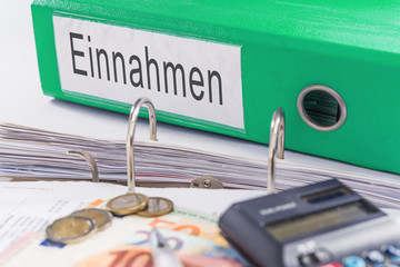 Aktenordner mit Einnahmen, Geldscheinen, Münzen und Taschenrechner