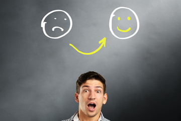 From sad to happy emoticons. Young man choosing emotion