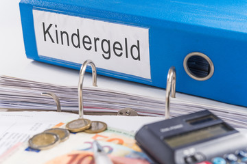 Aktenordner mit Kindergeld, Geldscheinen, Münzen und Taschenrechner