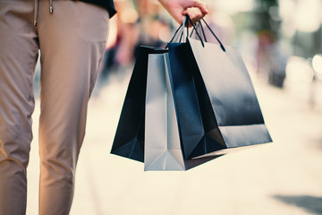 Close up of woman`s hand holding shopping bags while walking on the street.