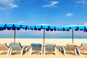 Blue beach umbrellas and loungers on the sandy seashore
