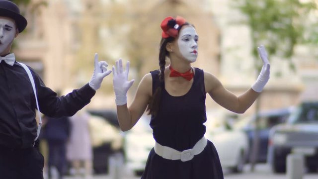 Man and woman mimes dancing at blurred urban street