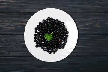 Black currant on wooden table with leaf sprig