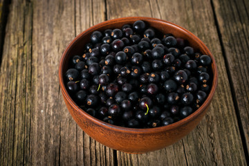 Black currant on wooden table with leaf sprig