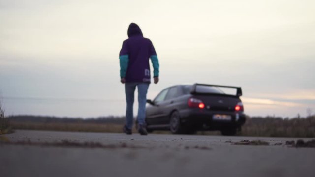 Blurred view of a young man walking to his sports car parked nearby