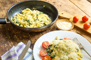 Delicious vegetarian dish - pasta fettuccine with spinach and cherry tomatoes on a rustic table