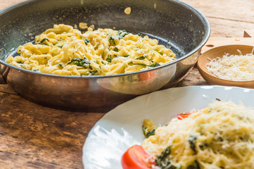 Delicious vegetarian dish - pasta fettuccine with spinach and cherry tomatoes on a rustic table