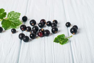 Black currant on wooden table with leaf sprig