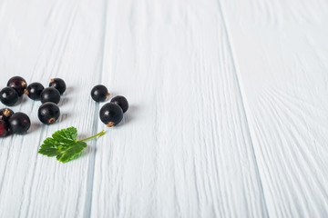 Black currant on wooden table with leaf sprig