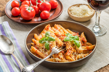 Pasta All'Arrabbiata - a traditional Italian dish with parmesan cheese and red wine on a rustic background