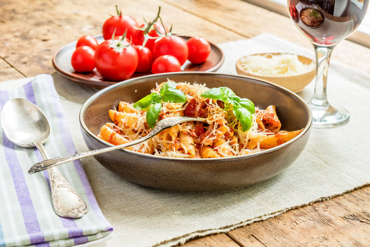 Pasta All'Arrabbiata - a traditional Italian dish with parmesan cheese and red wine on a rustic background