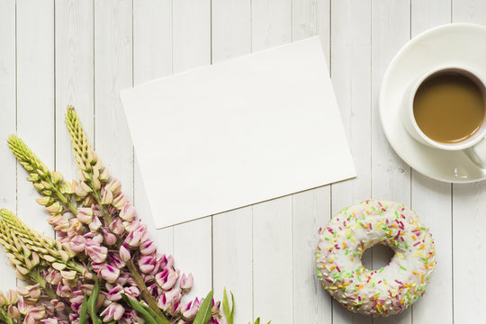 Fototapeta Still life with a Cup of coffee and lupine flowers donut on a light wooden table