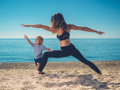 Mother doing yoga with toddler on beach