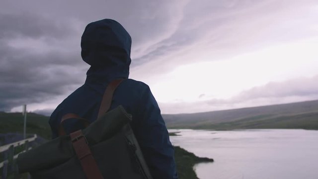 Man with a backpack enjoying view of stromy clouds over the lake, cinematic shot