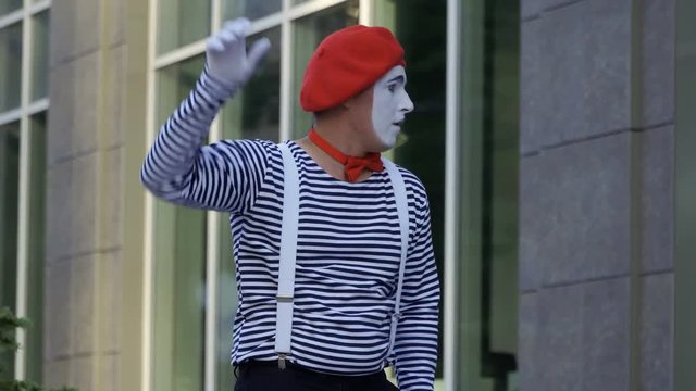 Funny mime looking at office window and communicates with people