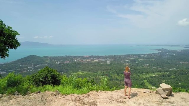 Aerial View of Female Photographer Taking Picture from Cliff with View of Tropical Island. Samui Island, Thailand