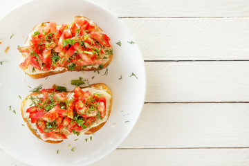 Bruschetta with fresh tomatoes and cheese on a white plate. Top view. Copy space