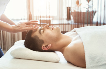 Obraz na płótnie Canvas Masseur doing head massage to man in salon