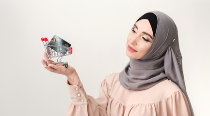 Buying concept. Arab woman with small trolley and credit card