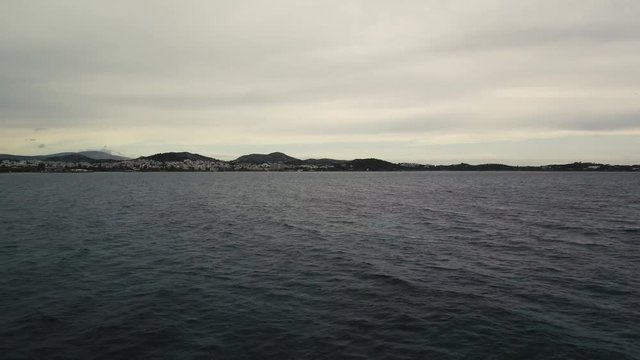 Flying over the sea on a cloudy day. Small island on the horizon.