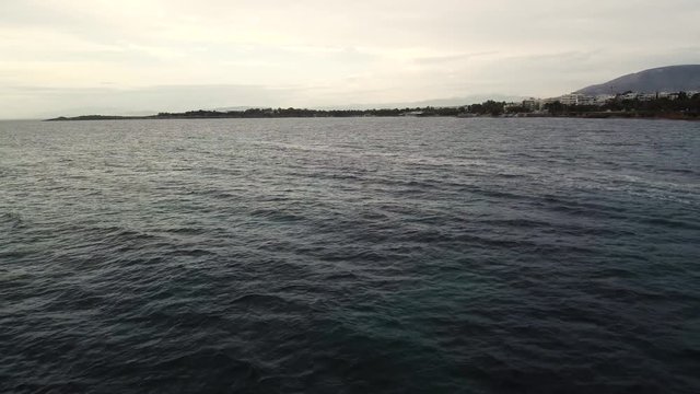 Flying over the sea on a cloudy day. Small island on the horizon.