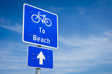 Simple blue bike lane sign indicating the direction to the beach
