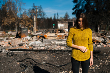 Young owner woman checking burned and ruined house and yard after fire, consequences of fire...