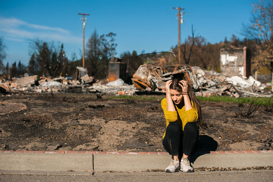 Sad Woman Home Owner Holds His Head By Hand Checking Burnt Out House And Yard After Fire Disaster, Consequences Of Fire Disaster Accident. Ruins After Fire Disaster, Loss And Despair Concept.