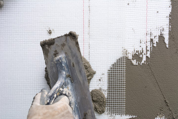 Fototapeta na wymiar Closeup hand construction plastering wet cement on expanded polystyrene