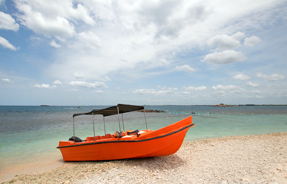 Bright orange panga / fishing boat on coral beach in Sri Lanka Asia