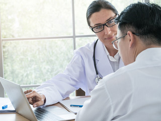 Female doctor in white medical coat with stethoscope giving a consultation to a patient and explaining medical informations.