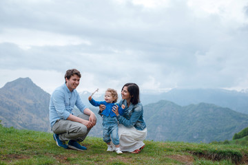 Happy smiling family of parents and their daughter spending time in beautiful mountains. Scenic landscape view