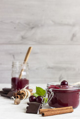 Fototapeta na wymiar Homemade cherry jam in a jars with fresh cherries on a light background.