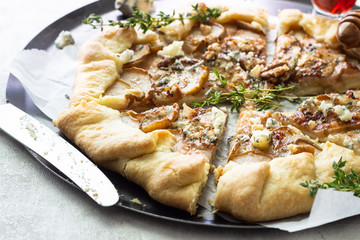 Homemade rustic galette with pears, blue cheese, walnuts and honey on light background. Gallette with a buttery crust and sweet fruit filling. Rustic style.