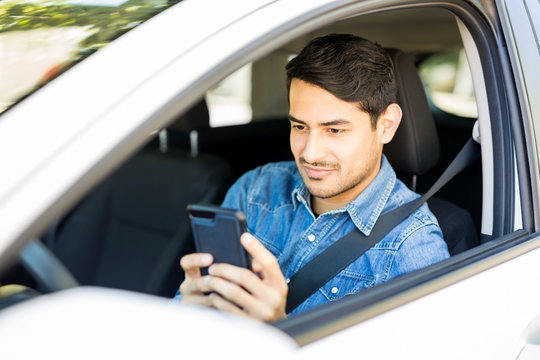 Young Man Using Mobile Phone In A Car