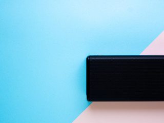 Black portable speaker wireless on blue and pink pastel color background. Flat lay, Top View