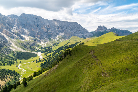 Italian Dolomites Landscape. Light after rain in Dolomites. Rocky peaks in the background surrounded by rain clouds. Mountain valley with layers of forest and mountains. Aerial view path trail hikeing