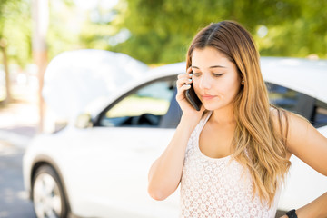 Woman calling someone for help with her broken car