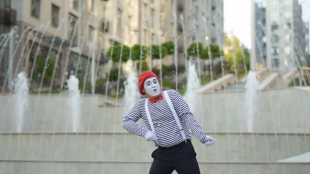 Funny mime pulling something invisible at fountains background