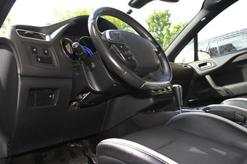 Steering wheel on the black car dashboard and driver's seat.