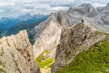 Fototapeta na wymiar Hiker on the ridge of Dolomites Mountains in Alps, Italy. Via ferrata trail. Peole on the rocky mountains path. Travel in Dolomites. Adventure in the mountains. Mountain climber on an exposed ledge